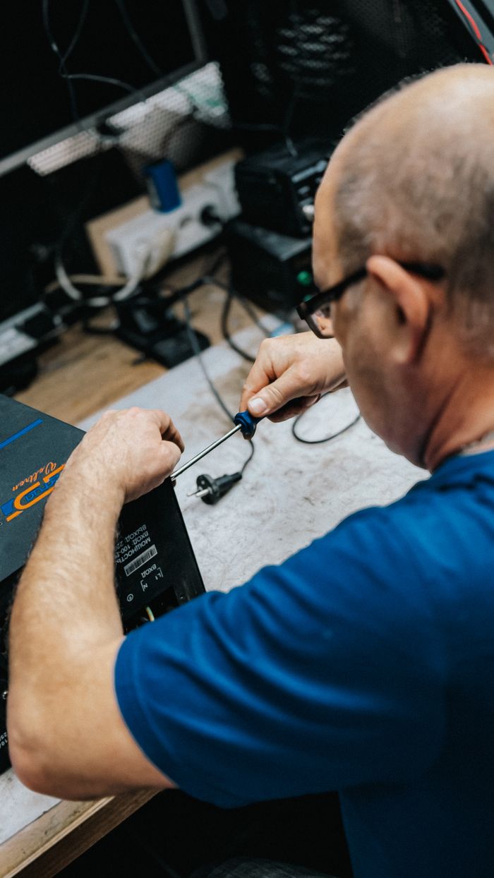 contact-img A skilled technician working on electronic repair tasks in a workshop environment.