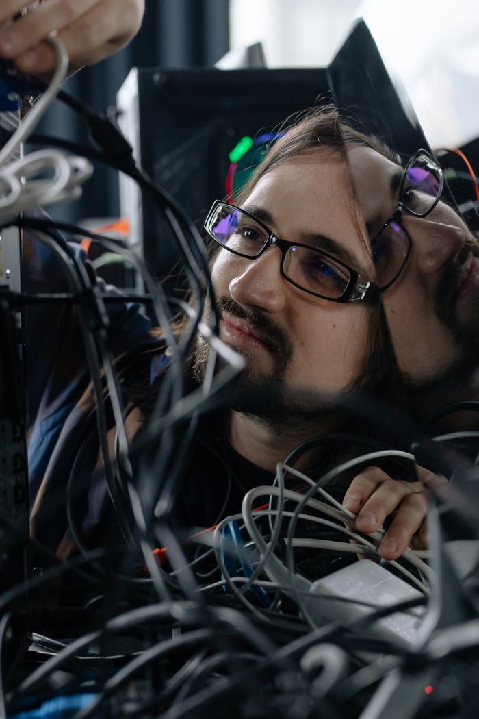 services-img A focused male system administrator adjusting tangled network cables indoors.