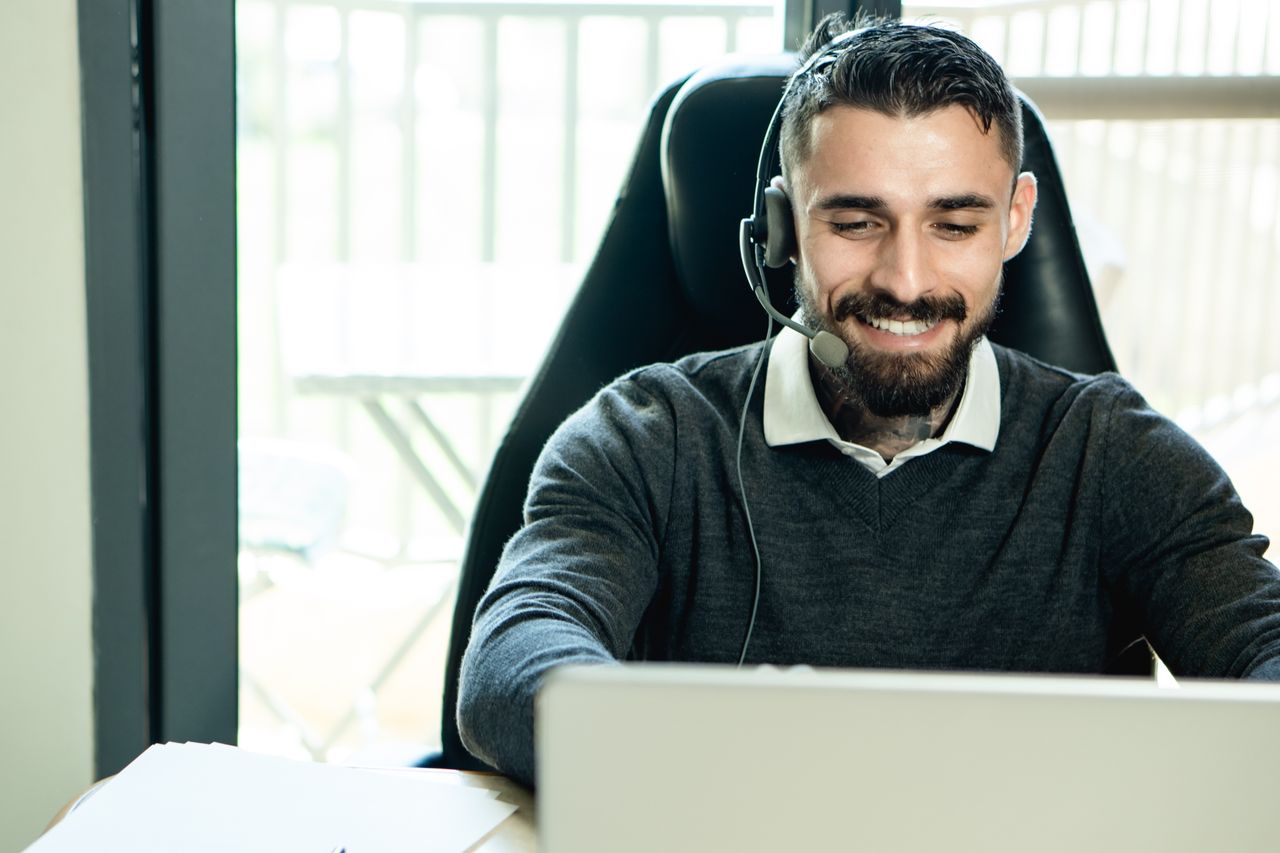 services-02 A friendly customer support agent wearing headphones, working in an office environment.