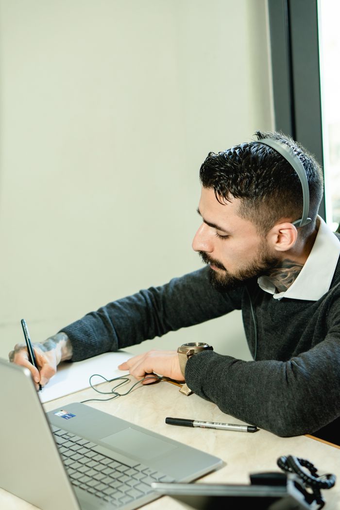 services-01 A man in an office using a laptop and headset, engaged in professional work.